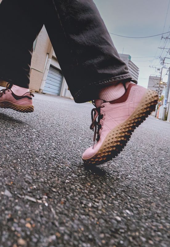 A person walking outdoors in pink Merrell barefoot shoes.